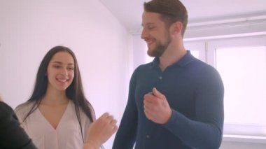 Genç beyaz çift, yeni dairelerinden anahtarları emlakçıdan heyecanla öperek alıyor..