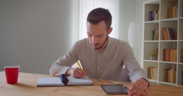 Zbliżenie portret młodego przystojnego kaukaski mężczyzna student studiów i korzystania z tabletu patrząc na aparat uśmiechnięty szczęśliwie w bibliotece kolegium — Wideo stockowe