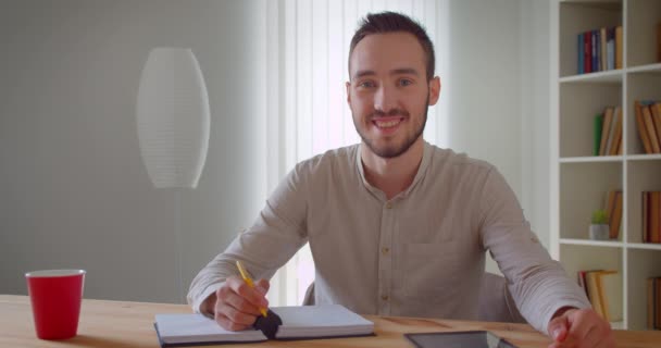 Zbliżenie portret młodego przystojnego kaukaski mężczyzna student studia i za pomocą tabletu patrząc na aparat uśmiechając się wesasowo w bibliotece kolegium w pomieszczeniu — Wideo stockowe