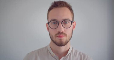 İzole arka plan ile mutlu bir şekilde gülümseyen kameraya bakan gözlüklü genç çekici adamın yakın çekim portresi