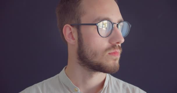 Närbild porträtt av unga stilig kaukasiska affärsman i glasögon tittar på kamera med bakgrund isolerad på grå — Stockvideo
