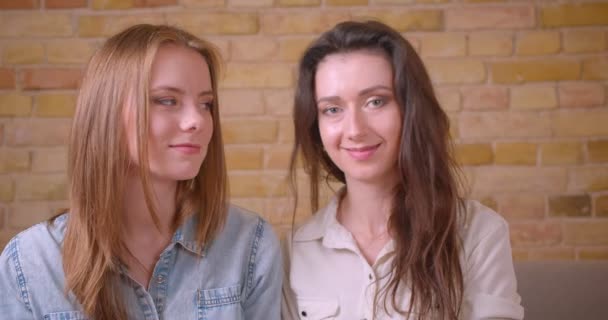 Closeup shoot of young beautiful lesbian couple smiling happily looking at camera sitting on the couch in a newly bought apartment — Stock Video