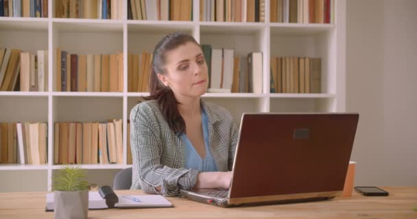 Tiro de close-up de jovem mulher de negócios caucasiana usando o laptop no escritório da biblioteca dentro de casa — Vídeo de Stock
