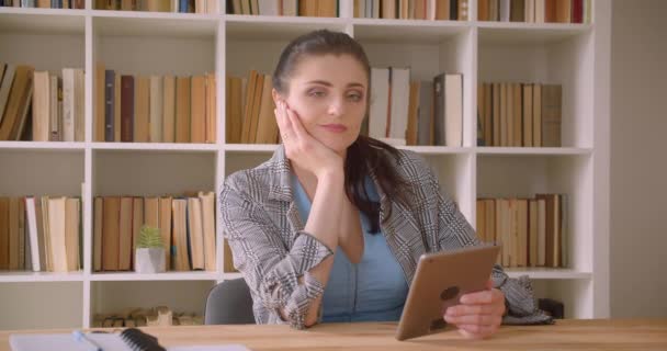 Kapalı kütüphane ofisinde tablet kullanarak genç kafkas iş kadını closeup çekim — Stok video