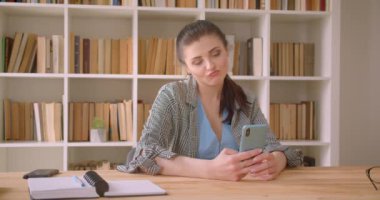 Kapalı kütüphane ofisinde telefon kullanarak genç kafkas iş kadını closeup çekim