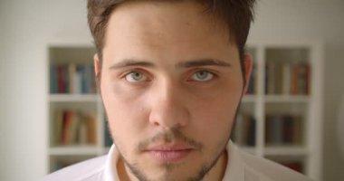 Arka planda kitaplıklar ile kütüphanede kameraya bakan yakışıklı beyaz erkek Closeup portre