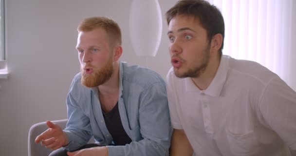 Primo piano ritratto di due uomini caucasici belli adulti che guardano lo sport in TV arrabbiarsi e frustrarsi seduti sul divano al chiuso — Video Stock