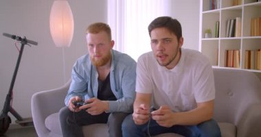 İki yetişkin yakışıklı beyaz adamın kapalı koltukta heyecanla video oyunları oynarken ki yakın çekim portresi