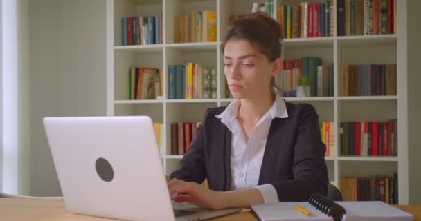 Primer plano de la joven mujer de negocios bastante caucásica trabajando en el ordenador portátil en la oficina en el interior — Vídeo de stock