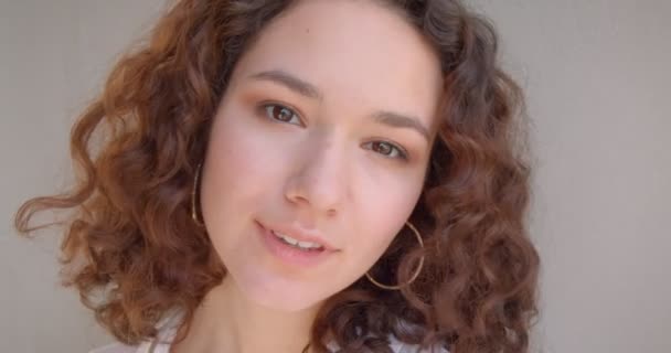 Retrato de cerca del joven modelo femenino caucásico rizado de pelo largo sonriendo felizmente mirando a la cámara con el fondo aislado en blanco — Vídeos de Stock