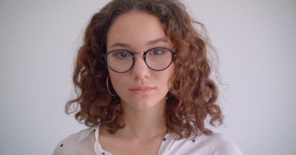 Κοντινό πλάνο του νεαρού χαριτωμένο μακριά μαλλιά σγουρά Καυκάσιος θηλυκό σε γυαλιά χαμογελώντας χαρούμενη κοιτάζοντας την κάμερα με φόντο απομονώνεται σε λευκό — Αρχείο Βίντεο