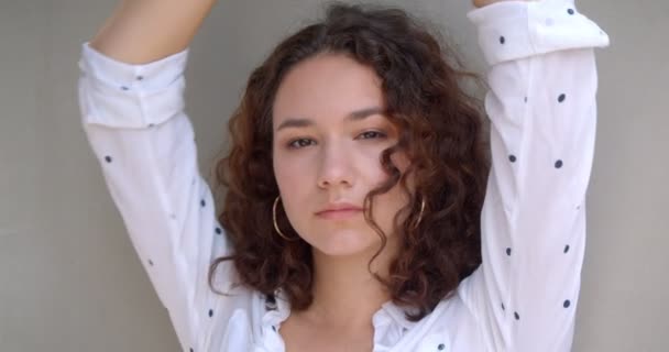 Closeup portré fiatal szép hosszú hajú göndör kaukázusi női modell nézi kamera háttérrel izolált fehér — Stock videók