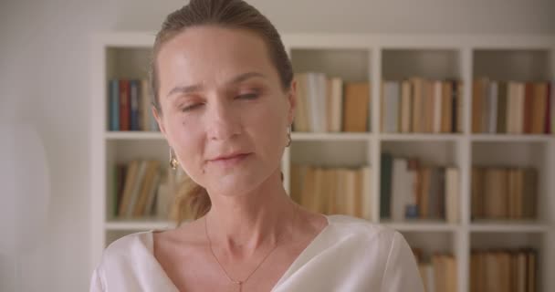 Primo piano ritratto di anziani caucasici bruna femminile guardando la fotocamera sorridente in biblioteca al chiuso — Video Stock