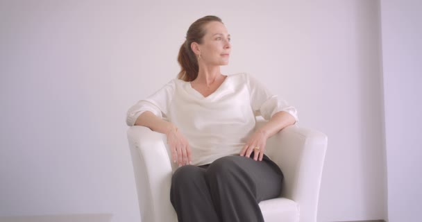 노인 백인 갈색 머리 여성의 클로즈업 초상화는 실내흰색 아파트에서 안락 의자에 앉아 — 비디오