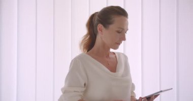 Tablet kullanarak yaşlı kafkas esmer iş kadının Closeup portre ve kapalı beyaz bir dairede duran kameraya yeşil renk ekran gösteren