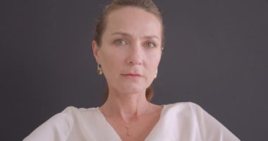 Üst düzey kafkas esmer kadın arka plan gri izole ile koltukta oturan kamera bakarak Closeup portre
