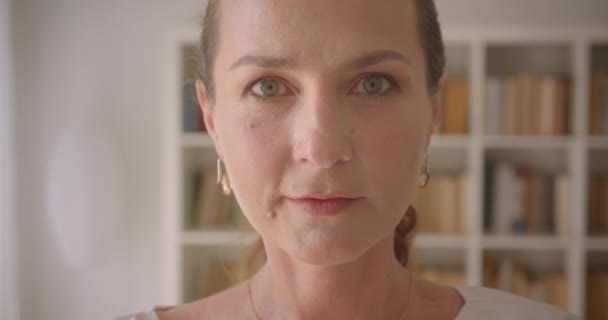 Gros plan macro portrait de vieux caucasien brunette femelle regardant la caméra souriant dans la bibliothèque à l'intérieur — Video