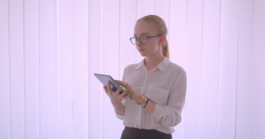 Tablet kullanarak gözlük genç güzel beyaz sarışın kız öğrencicloseup portre ve beyaz daire de kapalı duran kameraya yeşil ekran gösteren