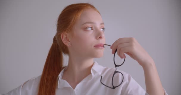 Closeup portré fiatal aranyos kaukázusi vörös hajú nő nézi kamera ül a karosszékben egy fehér szobában — Stock videók