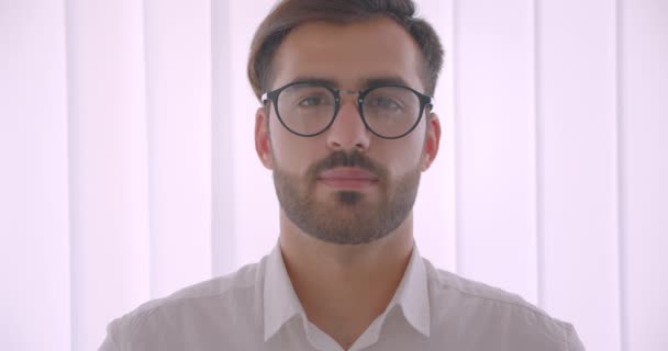 Nahaufnahme Porträt eines gut aussehenden erfolgreichen kaukasischen Geschäftsmannes mit Brille, der im weißen Büro drinnen glücklich in die Kamera lächelt — Stockvideo