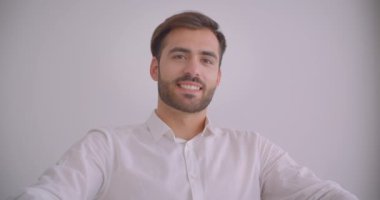 Yetişkin yakışıklı sakallı kafkas işadamının kapalı beyaz ofiste koltukta mutlu bir şekilde otururken kameraya bakan closeup portresi