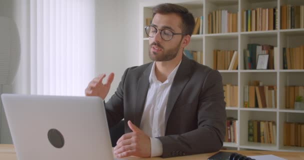 Primer plano retrato de adulto guapo barbudo caucásico hombre de negocios en gafas tener una videollamada en el portátil en la oficina en el interior — Vídeos de Stock