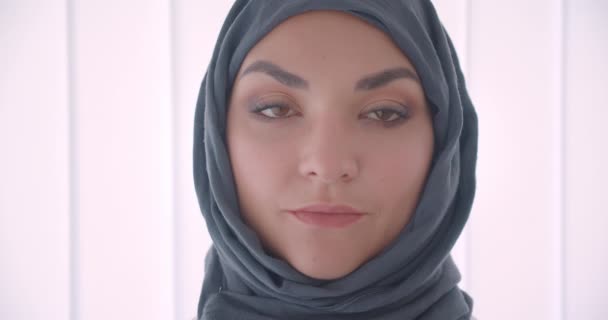 Nahaufnahme Porträt einer jungen muslimischen attraktiven Geschäftsfrau im Hidschab, die im weißen Büro drinnen in die Kamera blickt — Stockvideo