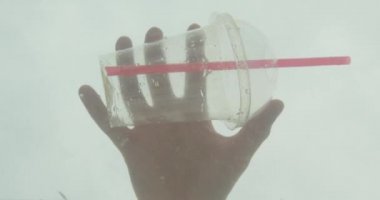 Okyanus suyunda plastik bir şişe atma erkek el closeup ateş