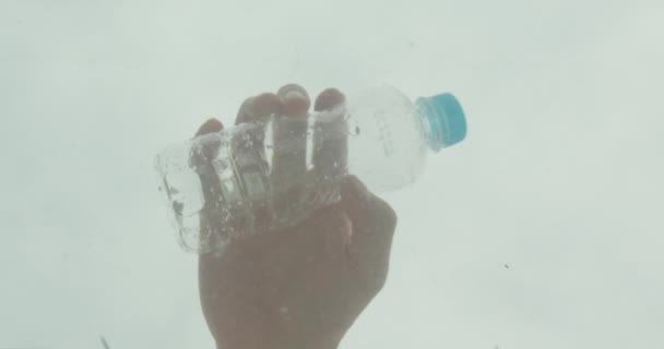 Primo piano tiro di mano maschile gettando una bottiglia di plastica nell'acqua dell'oceano. Il problema dell'inquinamento — Video Stock