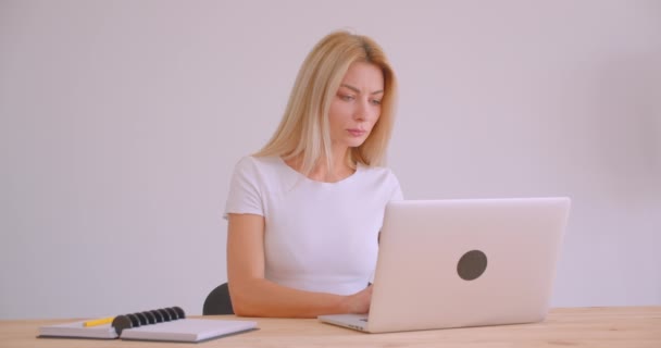 Крупним планом портрет дорослої білошкірої бізнес-леді, яка використовує ноутбук в приміщенні в офісі — стокове відео