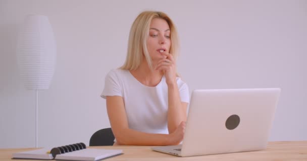 Nahaufnahme Porträt einer erwachsenen kaukasischen blonden Geschäftsfrau mit einem Videoanruf auf dem Laptop drinnen im Büro — Stockvideo