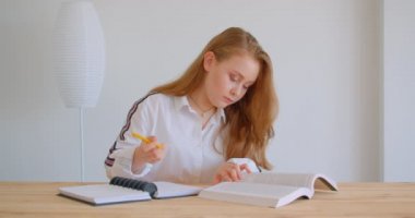 Genç güzel beyaz kız okuyan ve dairede kapalı notlar alma portre