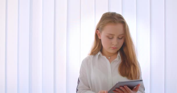 태블릿을 사용하여 아파트 실내에 서있는 카메라에 녹색 크로마 스크린을 보여주는 젊은 귀여운 백인 소녀의 클로즈업 초상화 — 비디오