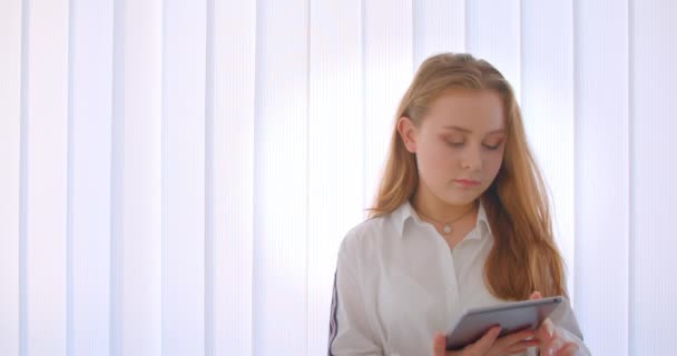 Primo piano ritratto di giovane ragazza caucasica carino utilizzando un tablet e mostrando schermo verde alla fotocamera in piedi all'interno dell'appartamento — Video Stock