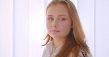 Genç güzel beyaz kız tornalama ve beyaz odada kamera kapalı bakarak closeup yan görünüm portre