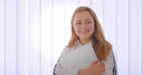 Портрет крупным планом молодой милой белой девушки с ноутбуком, стоящим в помещении в квартире — стоковое видео