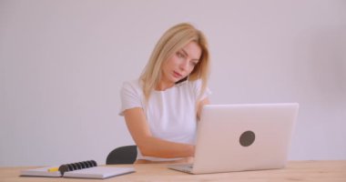 Ofis içinde bir telefon görüşmesi olan laptop kullanarak yetişkin beyaz sarışın çalışanın kapatmak portre