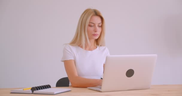 Primo piano ritratto di adulto caucasico bionda donna d'affari utilizzando il computer portatile guardando la fotocamera al chiuso in ufficio — Video Stock