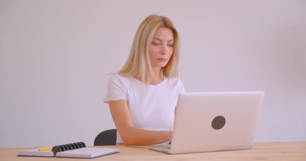 Primer plano retrato de adulto caucásico rubia mujer de negocios utilizando el portátil mirando a la cámara sonriendo alegremente en el interior de la oficina — Vídeo de stock