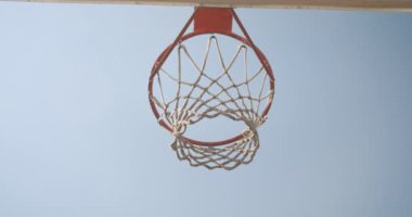 Arka planda gökyüzü ile mahkeme açık havada bir çember içine atılmış olmak basketbol topu görünümü portre aşağı closeup