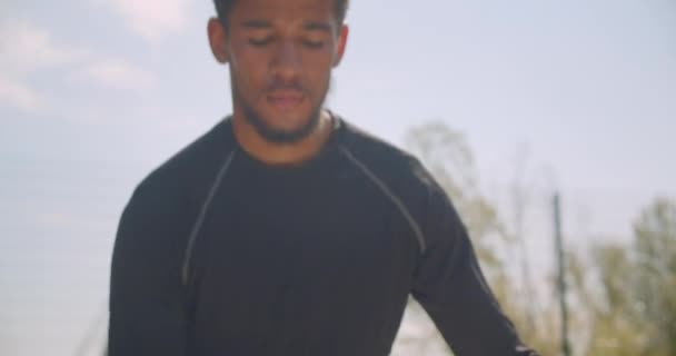 도시 야외에서 코트에서 워밍업 농구공을 들고 훈련하는 스포티한 아프리카계 미국인 남성 손의 클로즈업 초상화 — 비디오