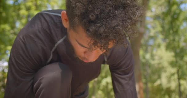 Portrait rapproché d'un jeune joggeur afro-américain se préparant à courir dans le parc à l'extérieur — Video