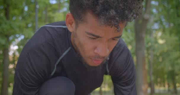 Primo piano ritratto di giovane forte afroamericano maschio jogger preparandosi a correre nel parco essendo motivato all'aperto — Video Stock