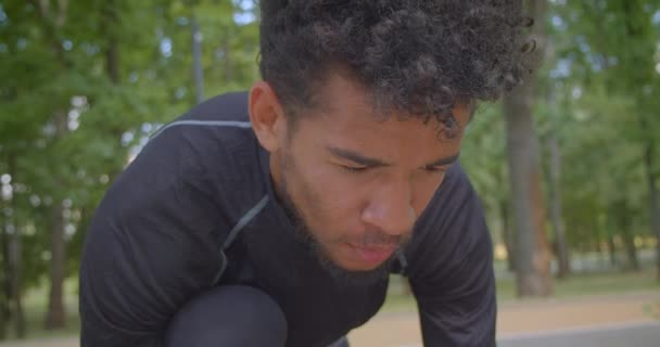 屋外で決定されている公園で実行する準備をしている若い強いアフリカ系アメリカ人の男性ジョガーのクローズアップ肖像画 — ストック動画