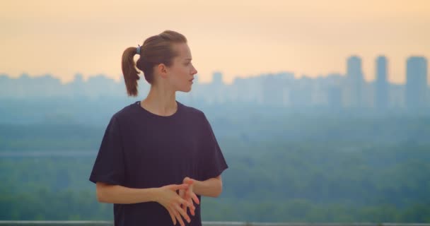 Retrato de close-up de jovem jogger feminino muito desportivo em uma camiseta preta olhando para a bela paisagem ao ar livre — Vídeo de Stock