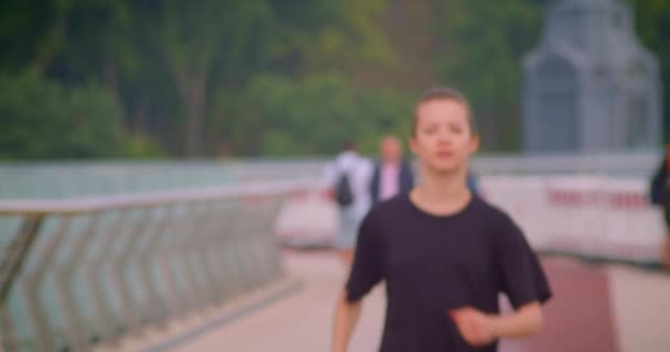 Zbliżenie portret młodego całkiem sportowy Jogger kobiet w czarnej t shirt działa na moście w miejskim mieście na zewnątrz — Wideo stockowe