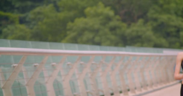 Nahaufnahme Frontporträt einer jungen hübschen, sportlichen Läuferin, die auf der Brücke in der Stadt im Freien joggt — Stockvideo