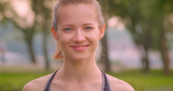 Closeup portré fiatal csinos, sportos női kocogó nézett kamera mosolygott boldogan a parkban a városi város a szabadban — Stock videók