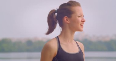 Arka planda açık havada mavi gökyüzü ile ileriye bakarak genç güzel sportif kadın koşucunun portre