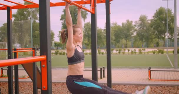 Retrato de cerca de una joven chica bastante deportiva haciendo ejercicios en el campo de atletismo en la ciudad urbana al aire libre — Vídeos de Stock